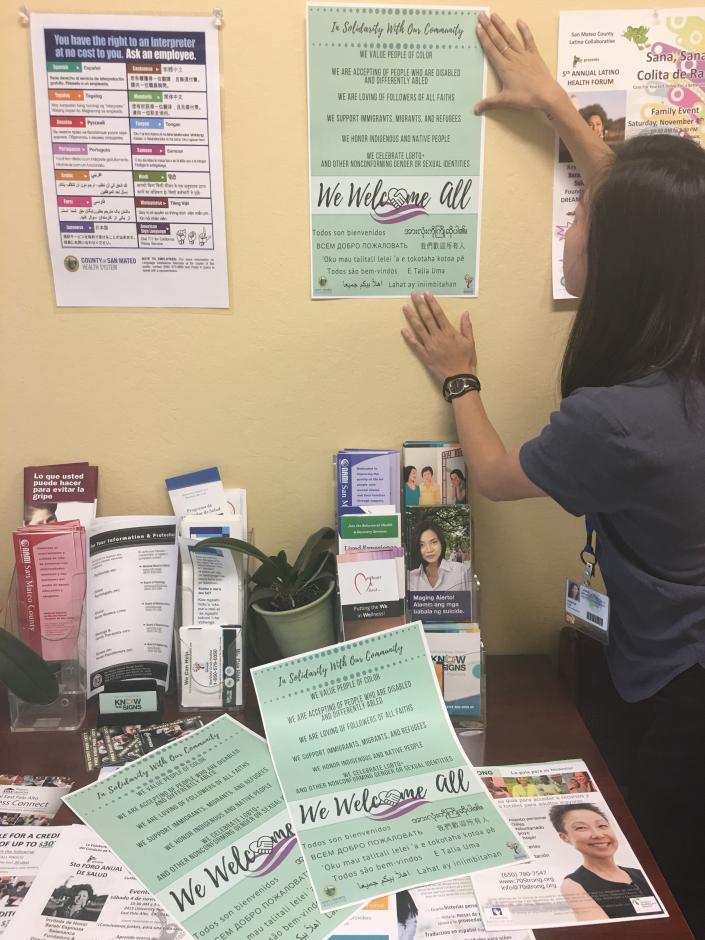 ODE Staff putting up "We Welcome All" poster