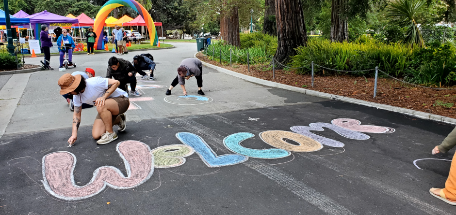 Chalk drawing of "Welcome" with someone coloring it in