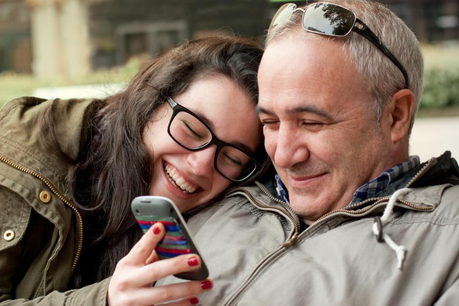 father and daughter looking at cell phone