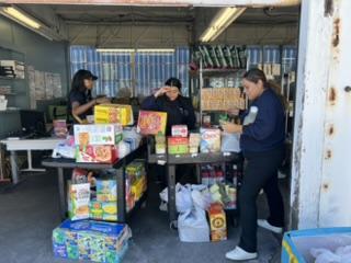 three women stocking groceries and household items