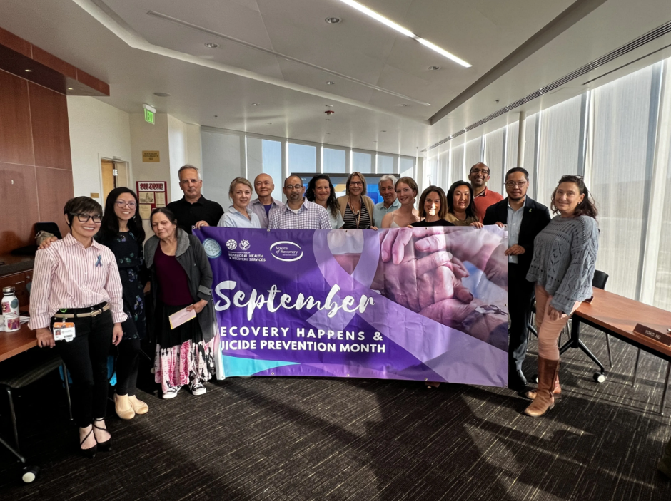group of people holding a banner that says "September, Recovery Happens and Suicide Prevention Month"